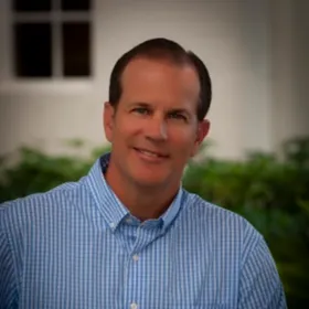 Roccy DeFrancesco, smiling, wearing a blue checked shirt.